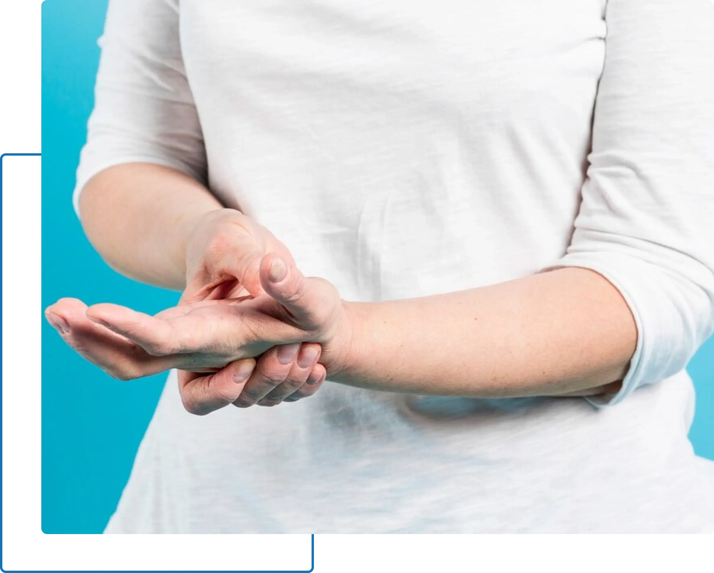 Person in a white shirt massaging their left wrist with their right hand against a blue background.